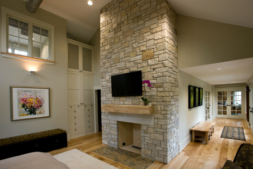 Design ideas for a mid-sized country open concept family room in Chicago with grey walls, light hardwood floors, a standard fireplace, a stone fireplace surround and a wall-mounted tv.