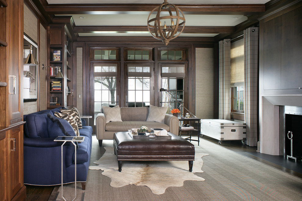 Inspiration for a mid-sized enclosed family room in New York with a library, brown walls, dark hardwood floors, a standard fireplace, a plaster fireplace surround, a concealed tv and brown floor.