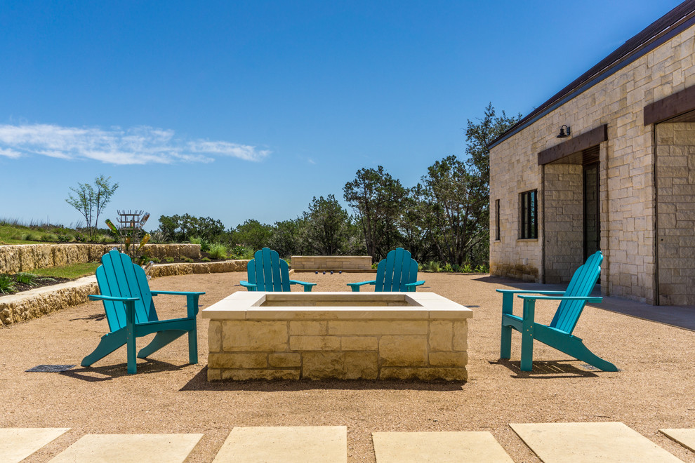 This is an example of a large country courtyard patio in Austin with a fire feature and gravel.