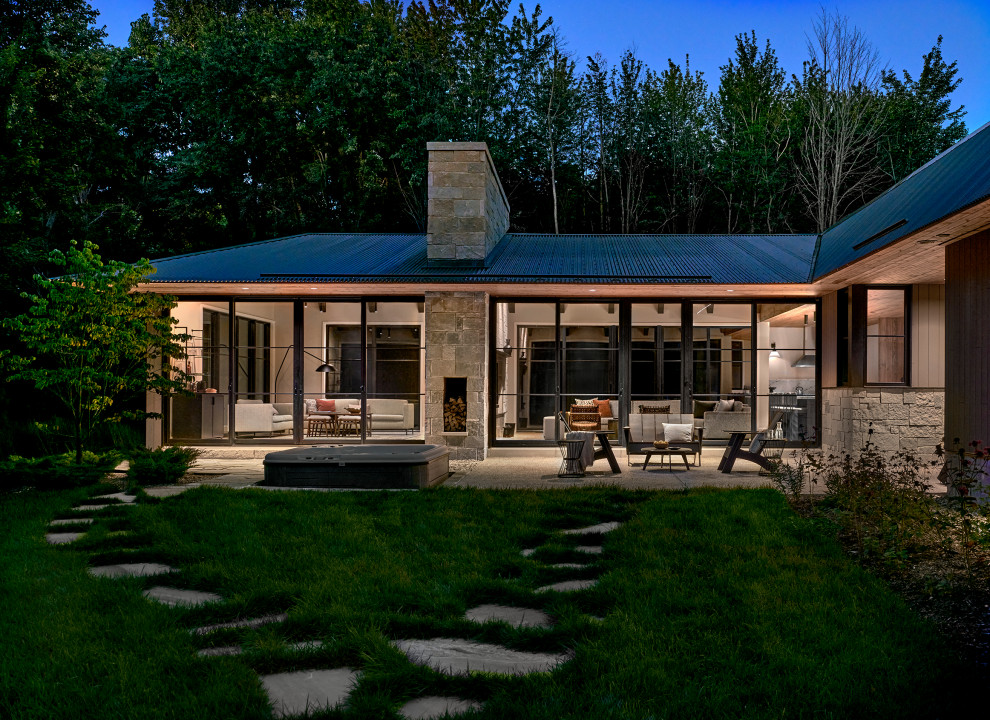 Example of a large cottage backyard stone patio design in Other with a roof extension