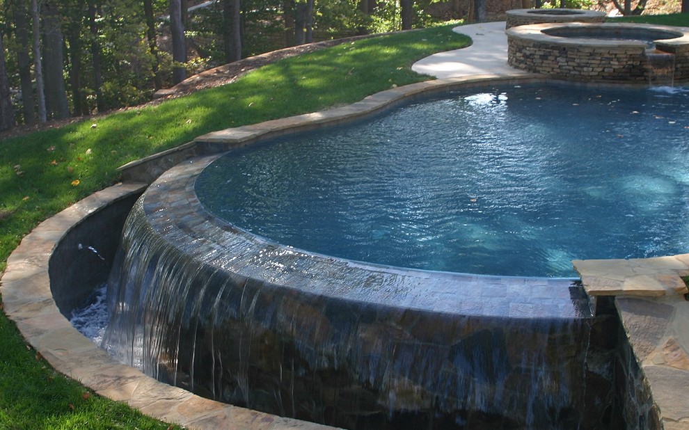 Hot tub - mid-sized transitional backyard concrete paver and custom-shaped infinity hot tub idea in Charlotte