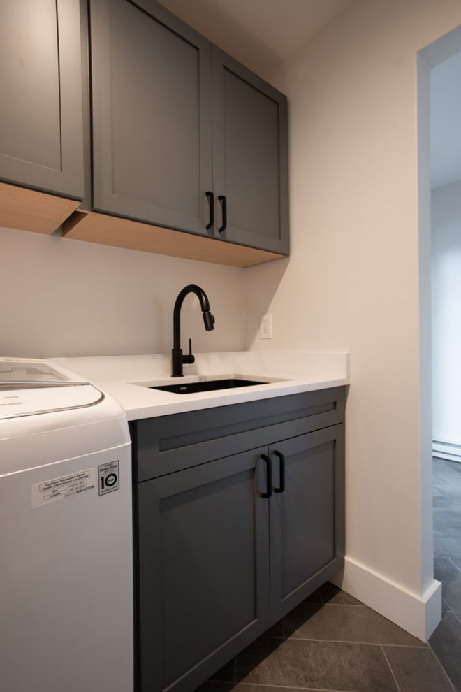 This is an example of a mid-sized contemporary single-wall utility room in Santa Barbara with an undermount sink, shaker cabinets, black cabinets, quartz benchtops, white walls and a side-by-side washer and dryer.