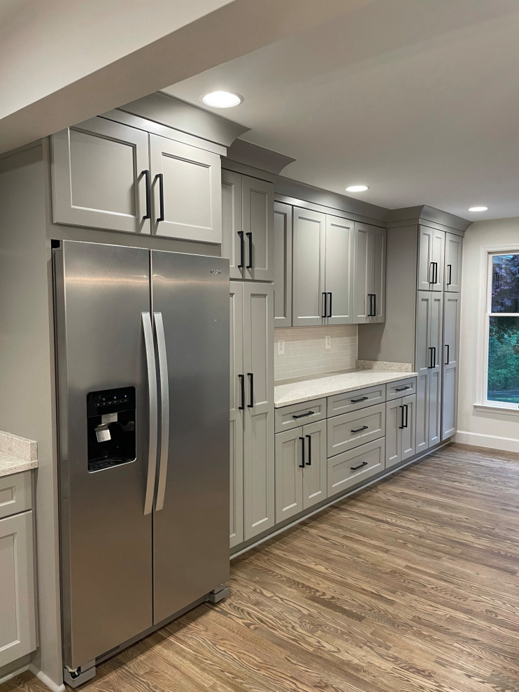 Photo of a modern eat-in kitchen in Other with an integrated sink, grey cabinets, quartzite benchtops, white splashback, brick splashback, stainless steel appliances, dark hardwood floors, with island, brown floor and multi-coloured benchtop.