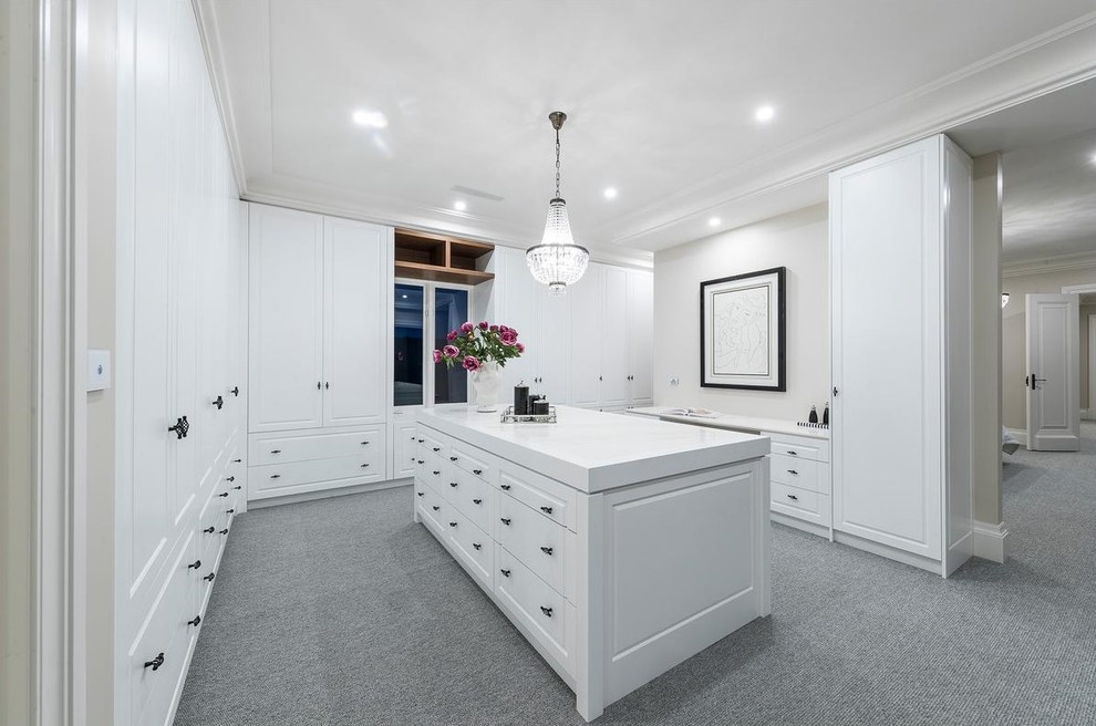 Large traditional gender-neutral walk-in wardrobe in Melbourne with raised-panel cabinets, white cabinets, carpet and grey floor.