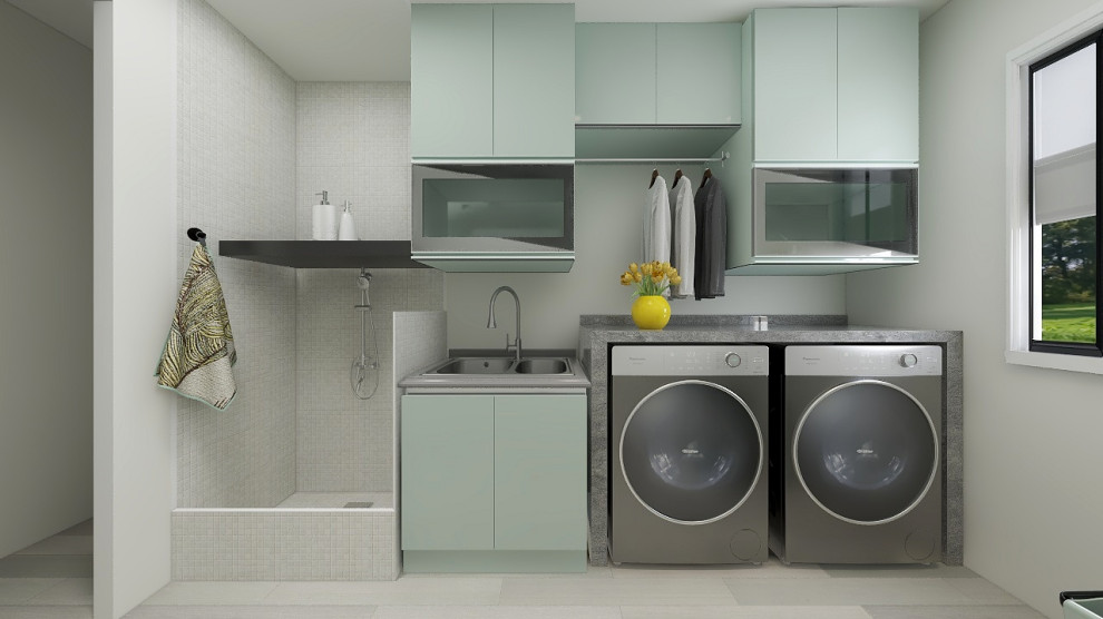 This is an example of a small modern single-wall utility room with a double-bowl sink, glass-front cabinets, green cabinets, granite benchtops, grey walls, ceramic floors, a side-by-side washer and dryer, grey floor and grey benchtop.