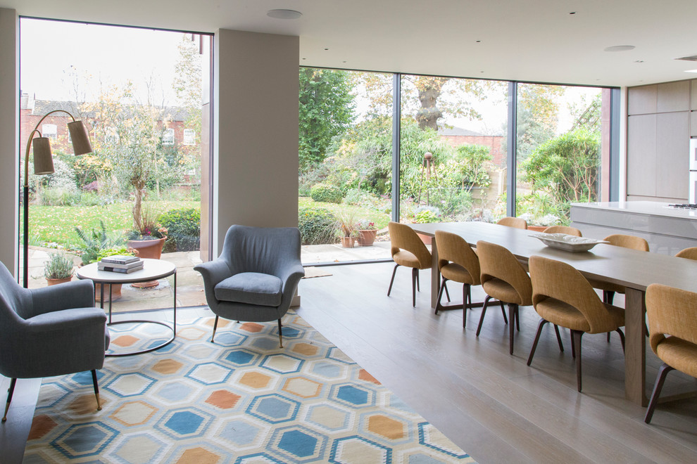Inspiration for a large midcentury open plan dining in London with beige walls, light hardwood floors and beige floor.
