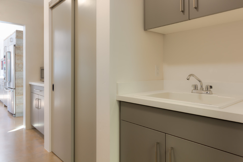 Inspiration for a mid-sized transitional u-shaped enclosed kitchen remodel in Phoenix with a drop-in sink, flat-panel cabinets, gray cabinets, solid surface countertops, stainless steel appliances and an island