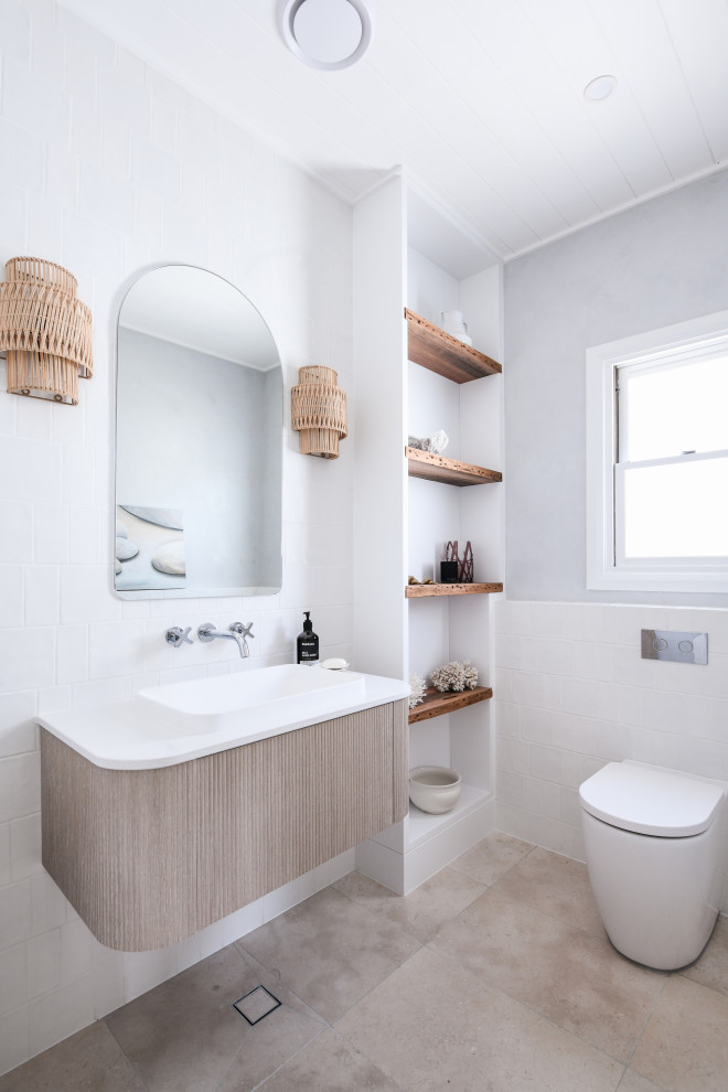Photo of a small beach style powder room in Sydney with beaded inset cabinets, light wood cabinets, a wall-mount toilet, white tile, porcelain tile, grey walls, porcelain floors, a drop-in sink, engineered quartz benchtops, beige floor, white benchtops and a floating vanity.