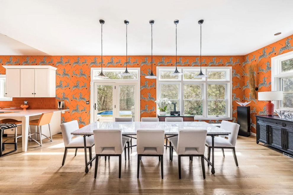 Esempio di una grande sala da pranzo aperta verso la cucina bohémian con pareti arancioni, parquet chiaro e pavimento beige