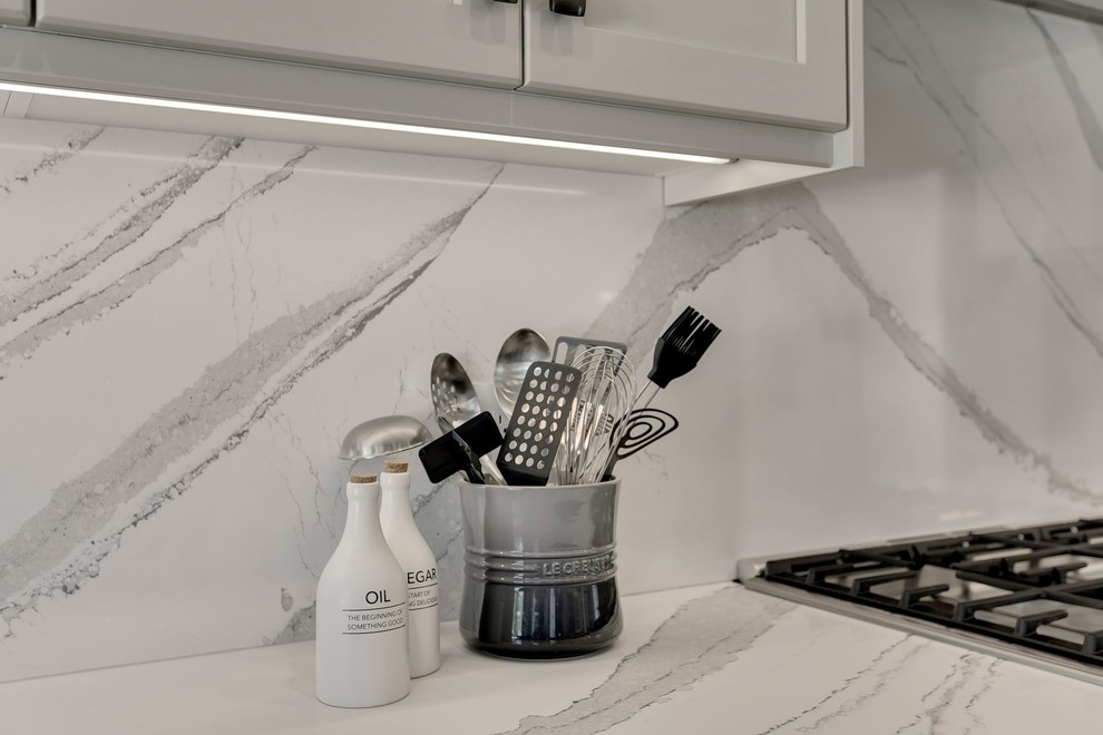 Large transitional u-shaped dark wood floor and brown floor eat-in kitchen photo in Calgary with an undermount sink, recessed-panel cabinets, gray cabinets, quartzite countertops, white backsplash, stone slab backsplash, stainless steel appliances, an island and white countertops