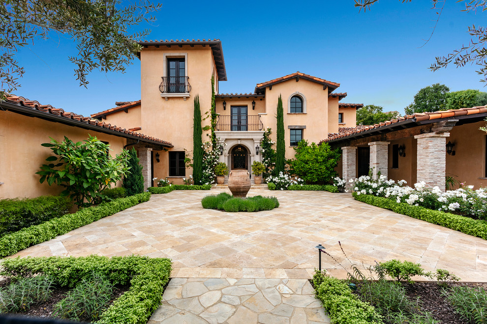 Photo of a mediterranean three-storey orange house exterior in Orange County with a gable roof and a tile roof.