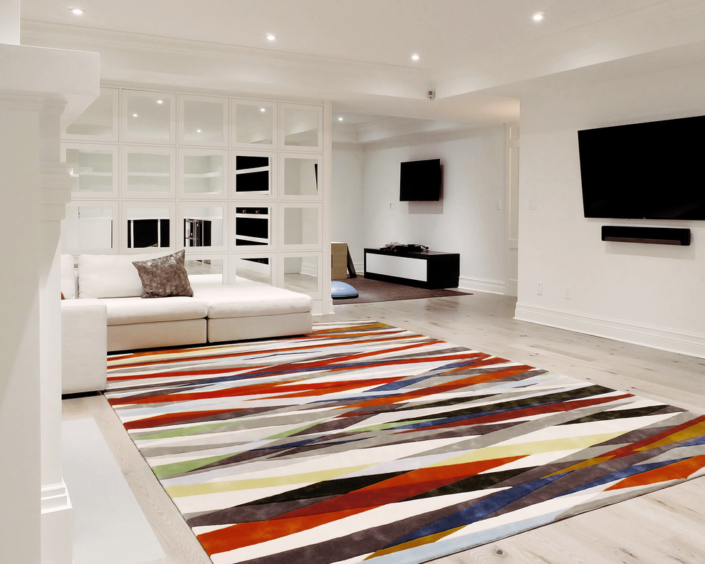 Large trendy underground light wood floor basement photo in Toronto with white walls and a standard fireplace