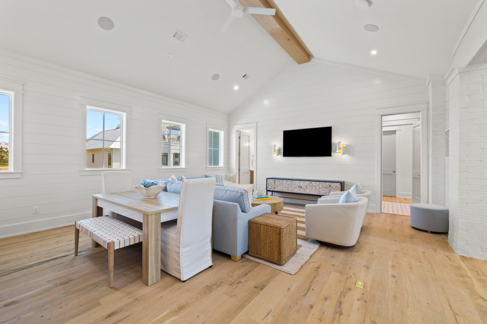 Ejemplo de sala de estar marinera con paredes blancas, suelo de madera clara, televisor colgado en la pared y machihembrado