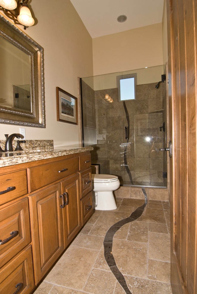 Photo of a large traditional kids bathroom in Phoenix with an undermount sink, raised-panel cabinets, dark wood cabinets, granite benchtops, a corner shower, a two-piece toilet, brown tile, stone tile, black walls and travertine floors.