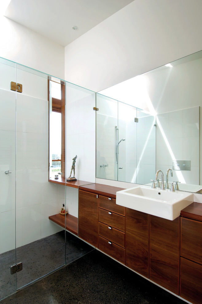 Inspiration for a small modern master bathroom in Melbourne with a vessel sink, flat-panel cabinets, dark wood cabinets, wood benchtops, a curbless shower, white tile, porcelain tile, white walls, concrete floors and brown benchtops.