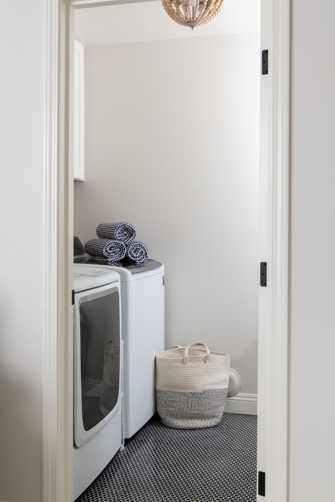 Bild på en stor vintage liten tvättstuga, med luckor med infälld panel, vita skåp, en tvättmaskin och torktumlare bredvid varandra och blått golv