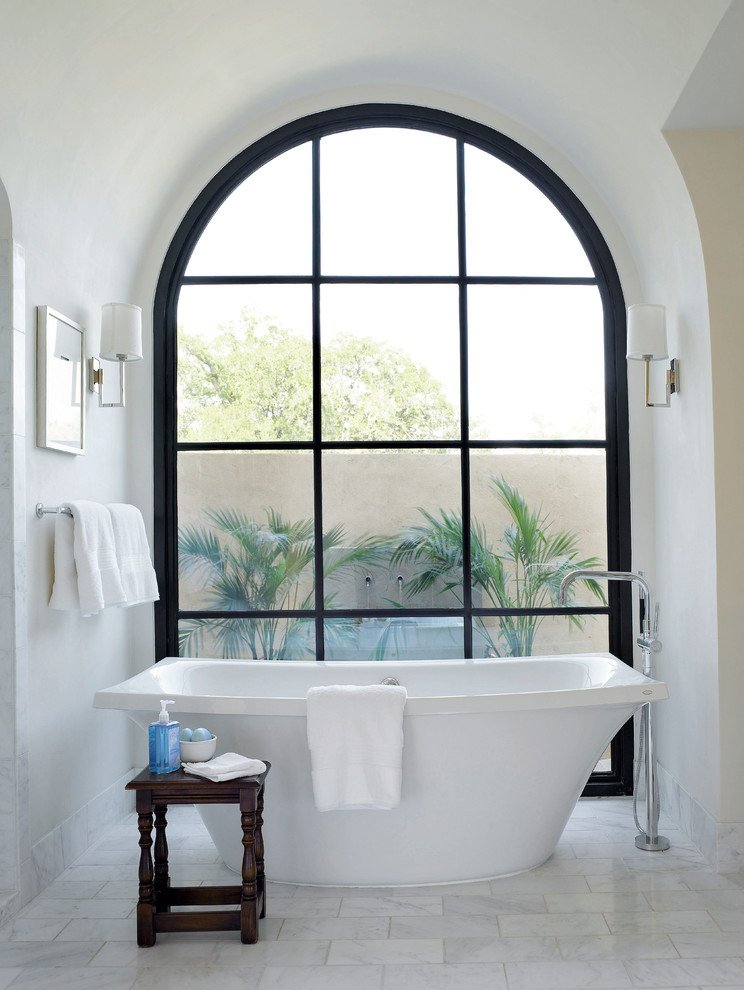 Design ideas for a mediterranean bathroom in Austin with a freestanding tub and white walls.