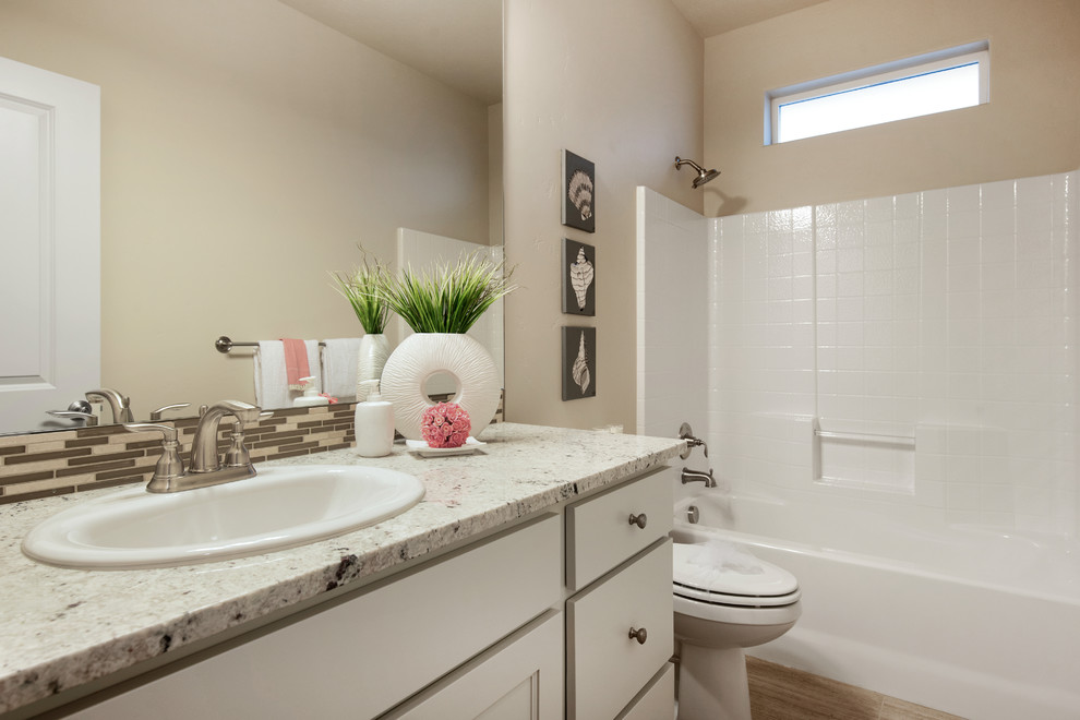 Photo of a mid-sized transitional kids bathroom in Boise with raised-panel cabinets, white cabinets, an alcove tub, a shower/bathtub combo, a two-piece toilet, beige tile, mosaic tile, beige walls, light hardwood floors, a drop-in sink and granite benchtops.