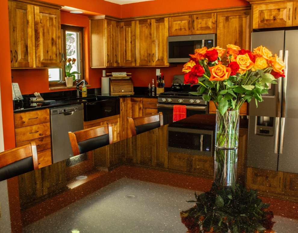 Example of a large mountain style u-shaped medium tone wood floor and brown floor open concept kitchen design with a farmhouse sink, raised-panel cabinets, medium tone wood cabinets, quartz countertops, stainless steel appliances, an island and black countertops