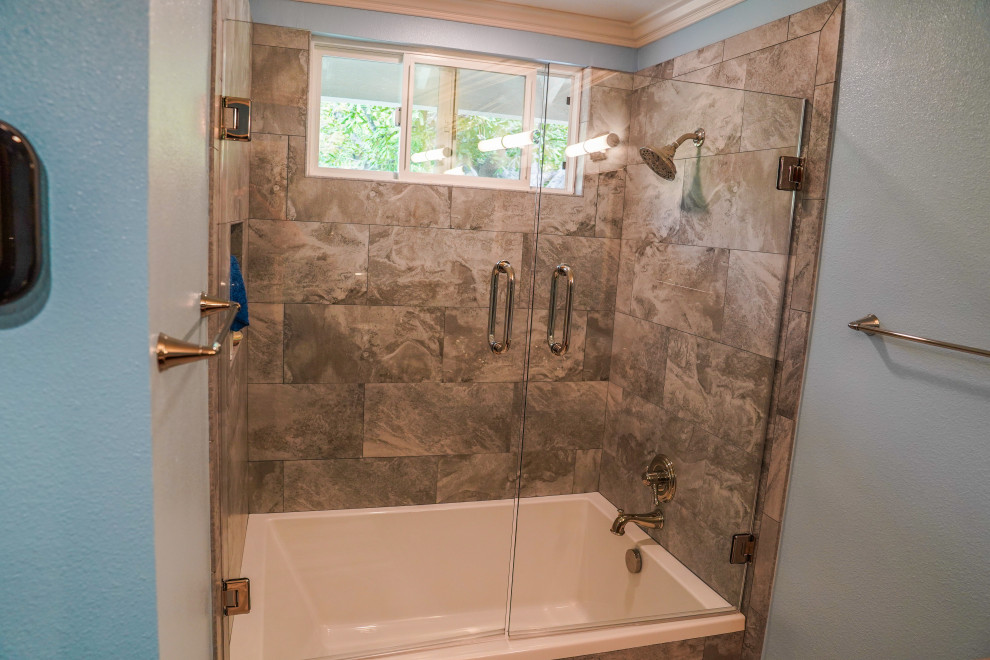 Example of a mid-sized transitional master double-sink tub/shower combo design in Orange County with a drop-in sink, marble countertops, a hinged shower door and beige countertops