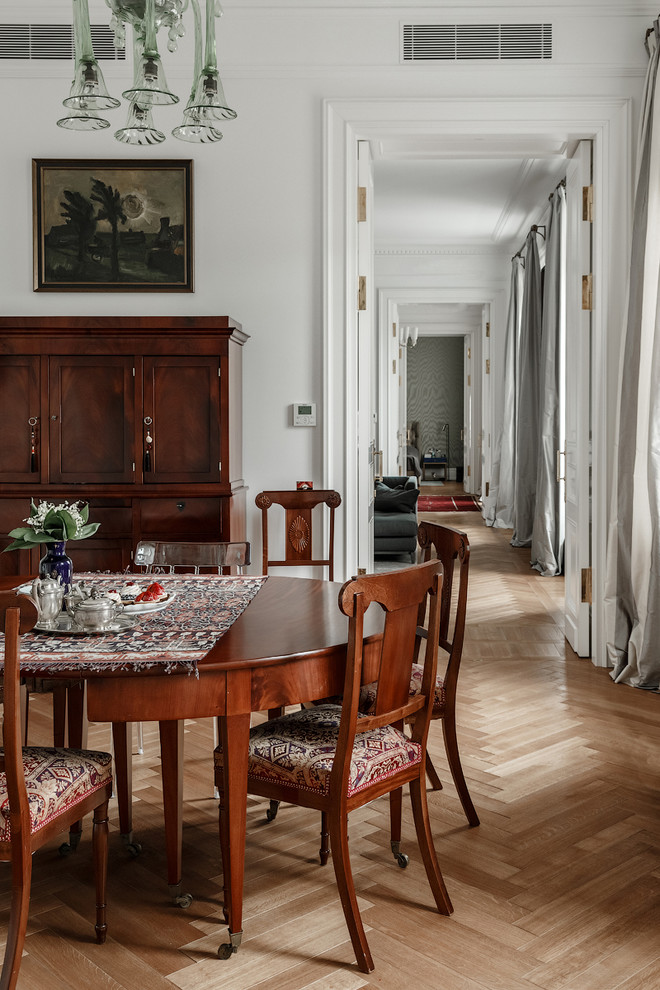 Design ideas for a traditional dining room in Moscow with white walls and light hardwood floors.