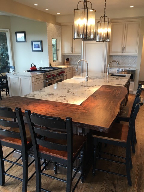 Example of a mid-sized transitional u-shaped medium tone wood floor kitchen design in Denver with a farmhouse sink, raised-panel cabinets, white cabinets, marble countertops, white backsplash, stone tile backsplash, paneled appliances and an island