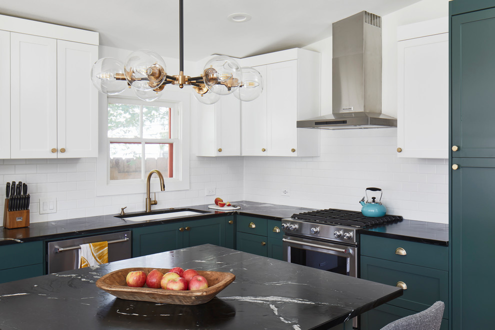 Inspiration for a mid-sized eclectic l-shaped medium tone wood floor and brown floor open concept kitchen remodel in Austin with an undermount sink, shaker cabinets, green cabinets, soapstone countertops, white backsplash, ceramic backsplash, stainless steel appliances, an island and black countertops
