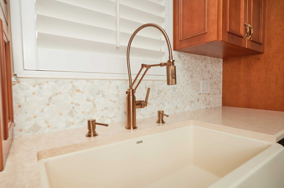 Mid-sized transitional galley porcelain tile, beige floor and tray ceiling kitchen photo with a farmhouse sink, recessed-panel cabinets, medium tone wood cabinets, quartz countertops, multicolored backsplash, marble backsplash, stainless steel appliances, a peninsula and beige countertops