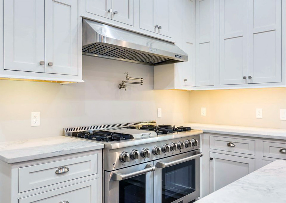 Kitchen pantry - large transitional l-shaped dark wood floor and brown floor kitchen pantry idea with a farmhouse sink, recessed-panel cabinets, white cabinets, quartz countertops, stainless steel appliances, an island and white countertops