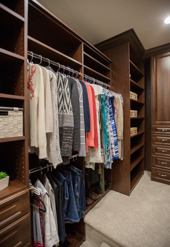 Mid-sized traditional gender-neutral walk-in wardrobe in Denver with raised-panel cabinets, medium wood cabinets, carpet and beige floor.