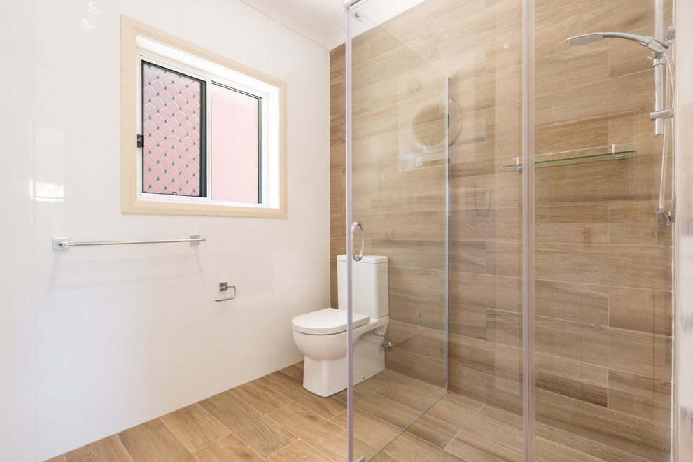 Small contemporary master bathroom in Sydney with furniture-like cabinets, medium wood cabinets, engineered quartz benchtops, a corner shower, a one-piece toilet, beige tile, ceramic tile and ceramic floors.