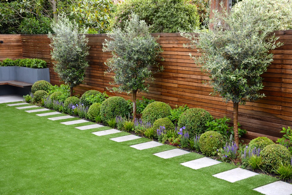 This is an example of a mid-sized traditional backyard garden in London with a vertical garden and natural stone pavers.