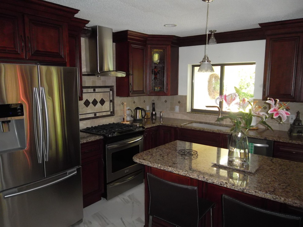 Inspiration for a mid-sized transitional l-shaped ceramic tile kitchen remodel with a drop-in sink, dark wood cabinets, granite countertops, stone tile backsplash, stainless steel appliances, an island and raised-panel cabinets