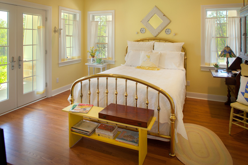Photo of a mid-sized country guest bedroom in Austin with yellow walls, medium hardwood floors and no fireplace.