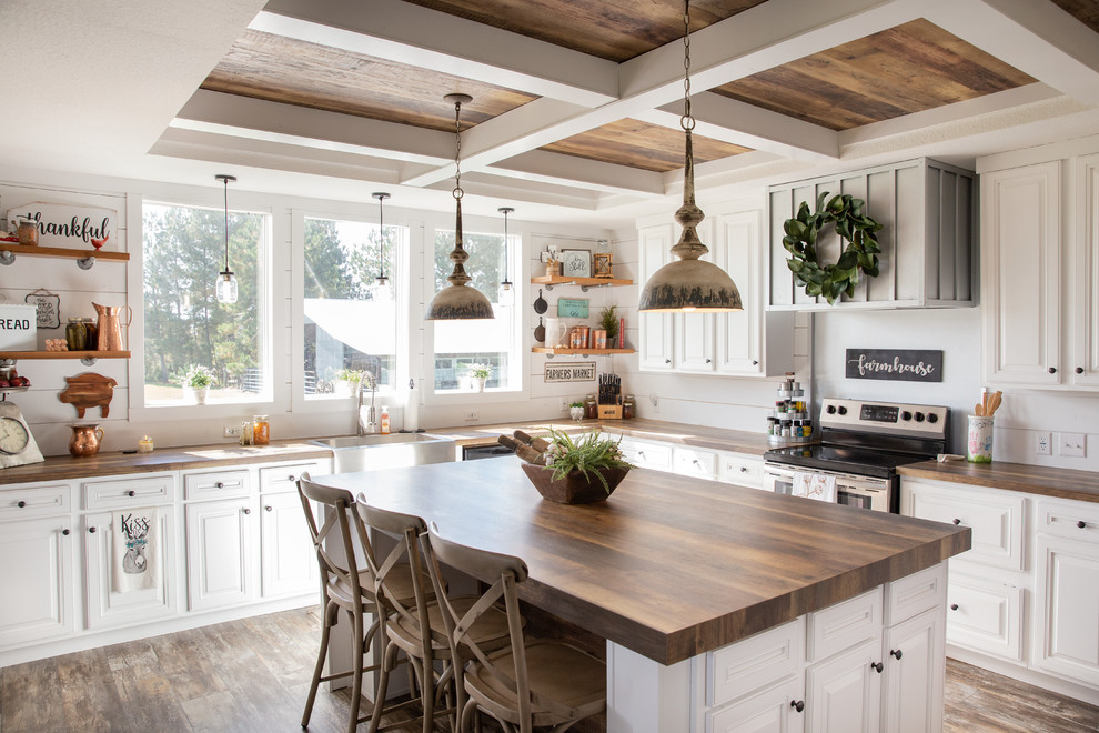 Photo of a country l-shaped kitchen in Other with a farmhouse sink, raised-panel cabinets, white cabinets, wood benchtops, white splashback, stainless steel appliances, medium hardwood floors and with island.