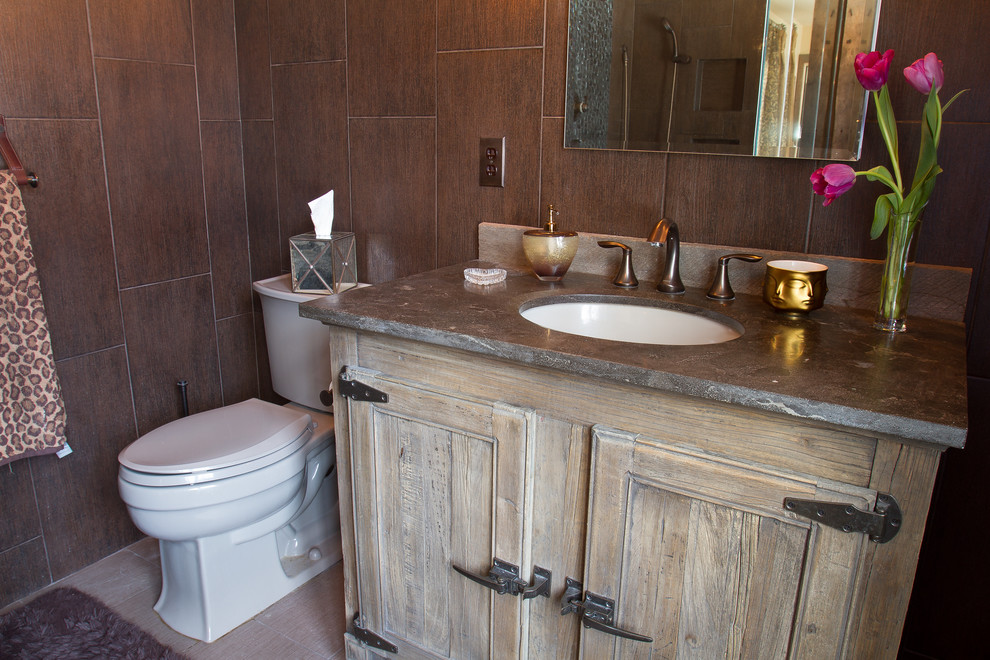 Inspiration for a mid-sized country master bathroom in New York with an undermount sink, recessed-panel cabinets, distressed cabinets, soapstone benchtops, a corner shower, a one-piece toilet, brown tile, pebble tile, brown walls and porcelain floors.