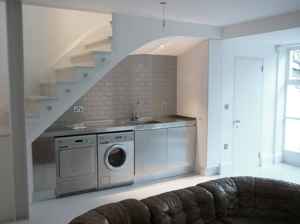 Photo of a medium sized classic single-wall utility room in London with an integrated sink, open cabinets, stainless steel worktops and grey walls.