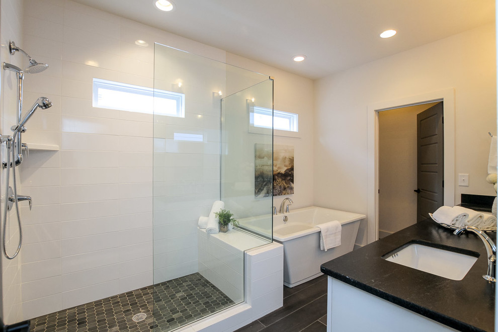This is an example of a large modern master bathroom in Nashville with flat-panel cabinets, white cabinets, a freestanding tub, a corner shower, a two-piece toilet, white tile, subway tile, white walls, porcelain floors, an undermount sink, granite benchtops, brown floor and a hinged shower door.