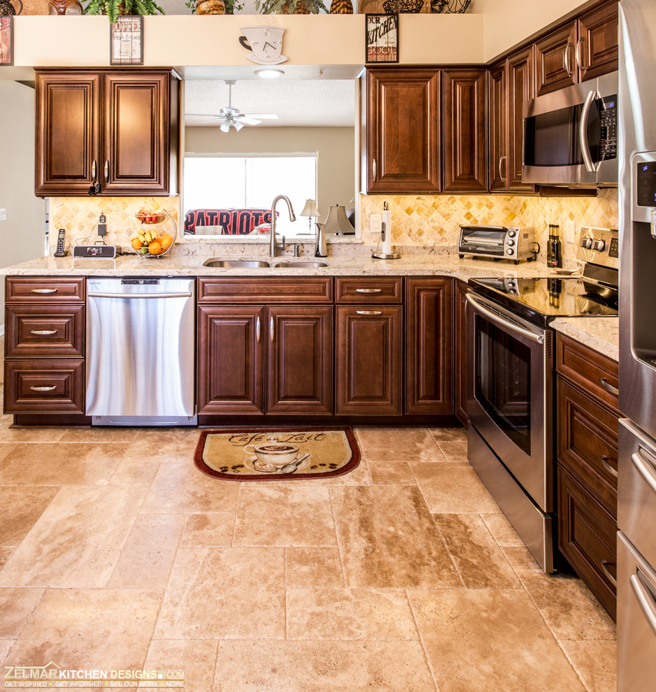 Inspiration for a mid-sized traditional l-shaped eat-in kitchen in Orlando with an undermount sink, raised-panel cabinets, dark wood cabinets, quartz benchtops, beige splashback, stone tile splashback, travertine floors and stainless steel appliances.