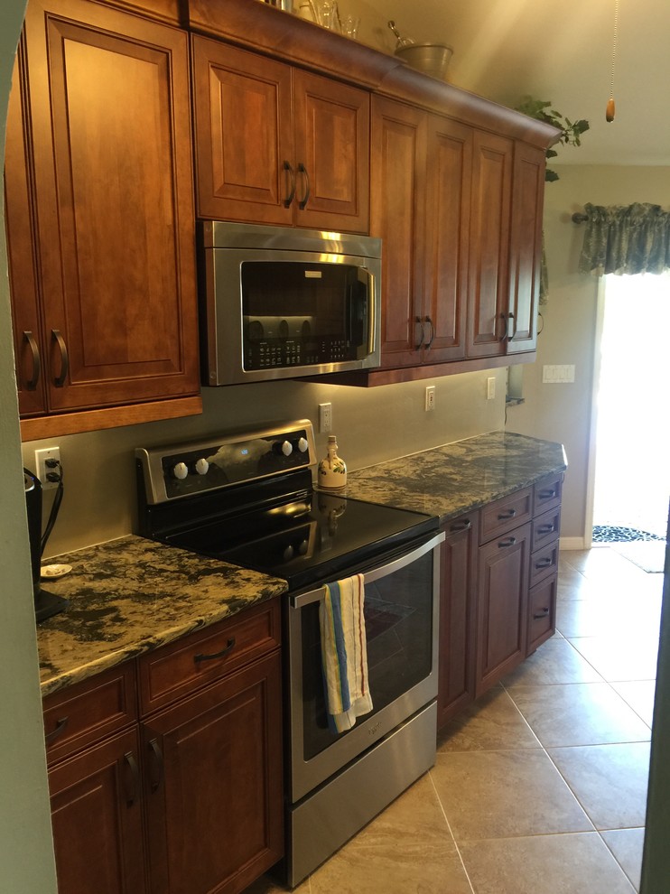 Mid-sized elegant porcelain tile kitchen photo in Miami with a single-bowl sink, raised-panel cabinets, medium tone wood cabinets, quartz countertops, beige backsplash, stainless steel appliances and an island