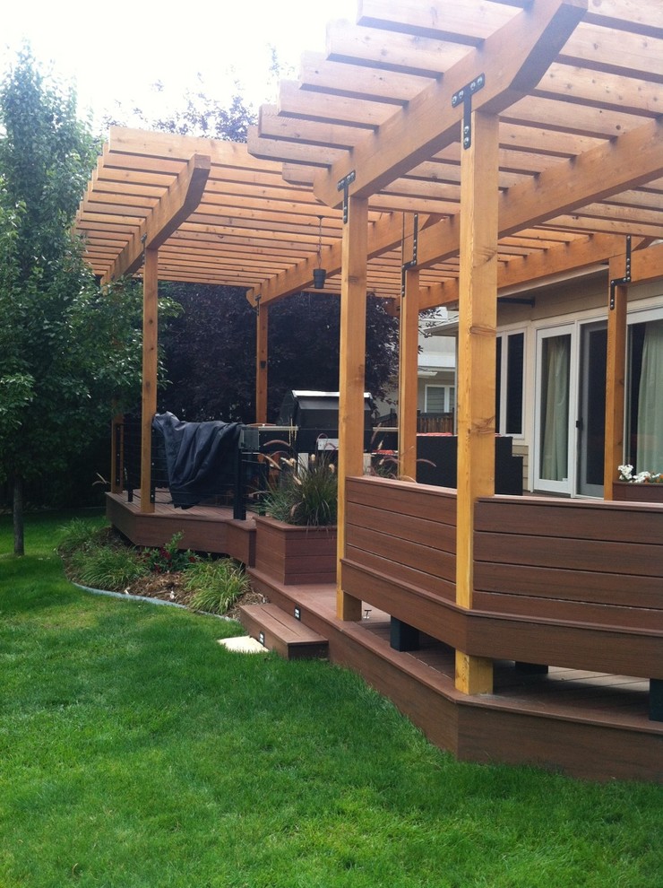 Large mountain style backyard deck photo in Denver with a pergola