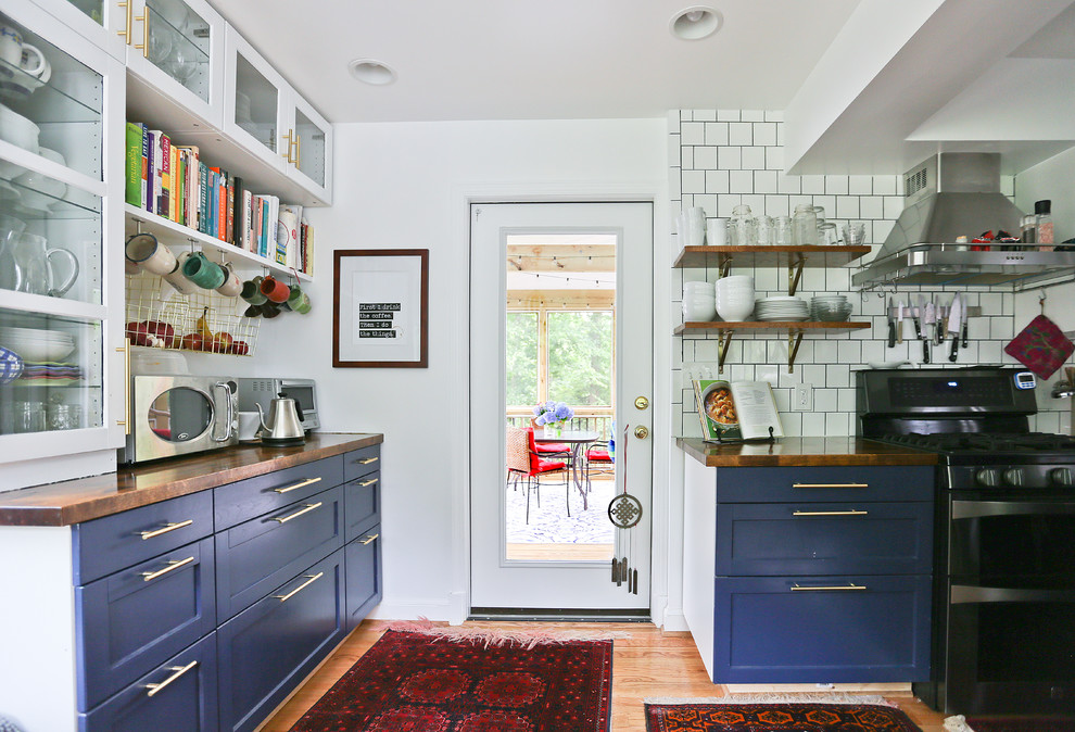 Design ideas for a small midcentury galley eat-in kitchen in DC Metro with recessed-panel cabinets, wood benchtops, white splashback, medium hardwood floors, brown benchtop and blue cabinets.