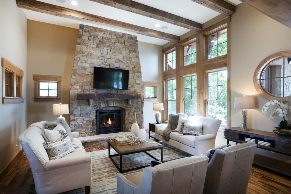 Inspiration for a large country open concept living room in Minneapolis with beige walls, medium hardwood floors, a standard fireplace, a stone fireplace surround, a wall-mounted tv and brown floor.