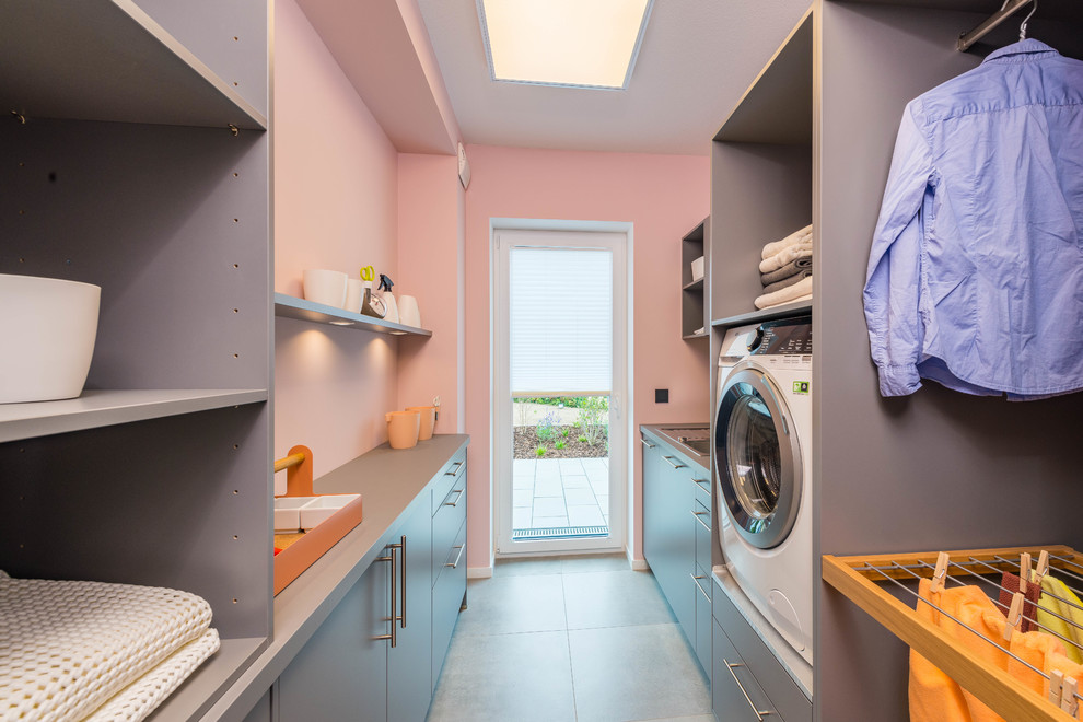 Inspiration for a mid-sized contemporary galley utility room in Other with a drop-in sink, flat-panel cabinets, grey cabinets, pink walls, grey floor and grey benchtop.
