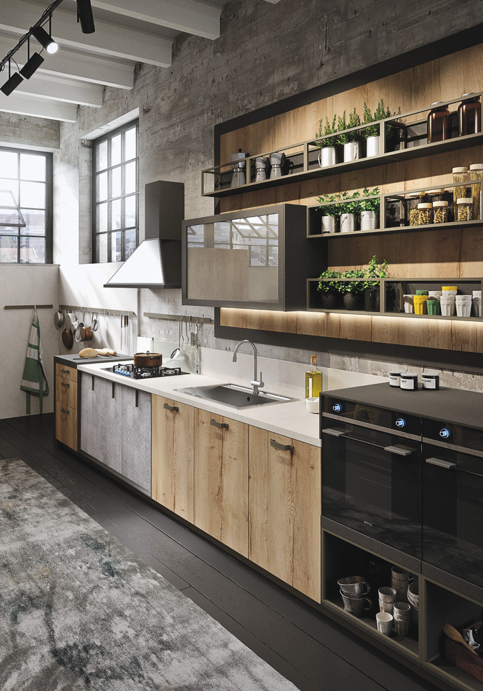 Mid-sized industrial l-shaped open plan kitchen in Marseille with an integrated sink, glass-front cabinets, light wood cabinets, concrete benchtops, grey splashback, cement tile splashback, black appliances, painted wood floors and with island.
