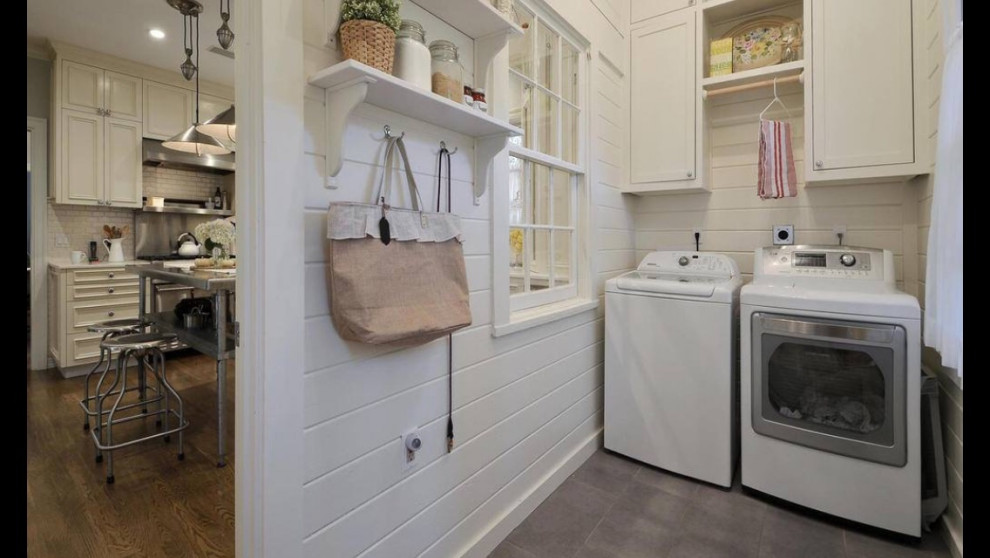 Photo of a country laundry room with shaker cabinets, porcelain floors, a side-by-side washer and dryer, grey floor and timber.