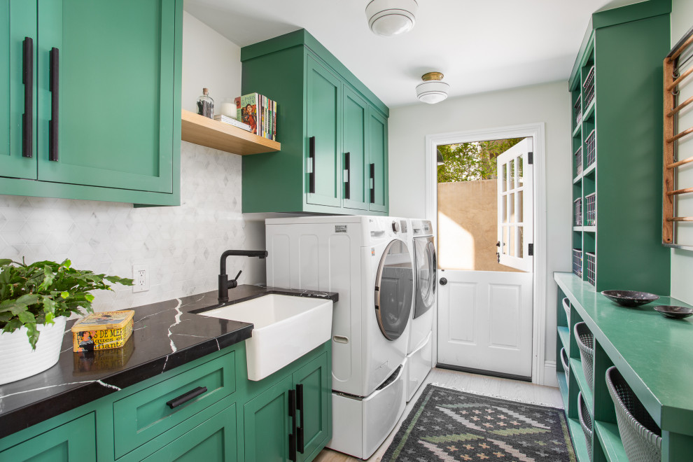 Transitional galley laundry room photo in Orange County with a farmhouse sink, shaker cabinets, green cabinets, white walls, a side-by-side washer/dryer and white countertops