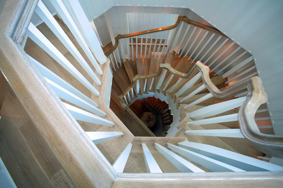 This is an example of an expansive beach style wood spiral staircase in Orange County with wood risers.