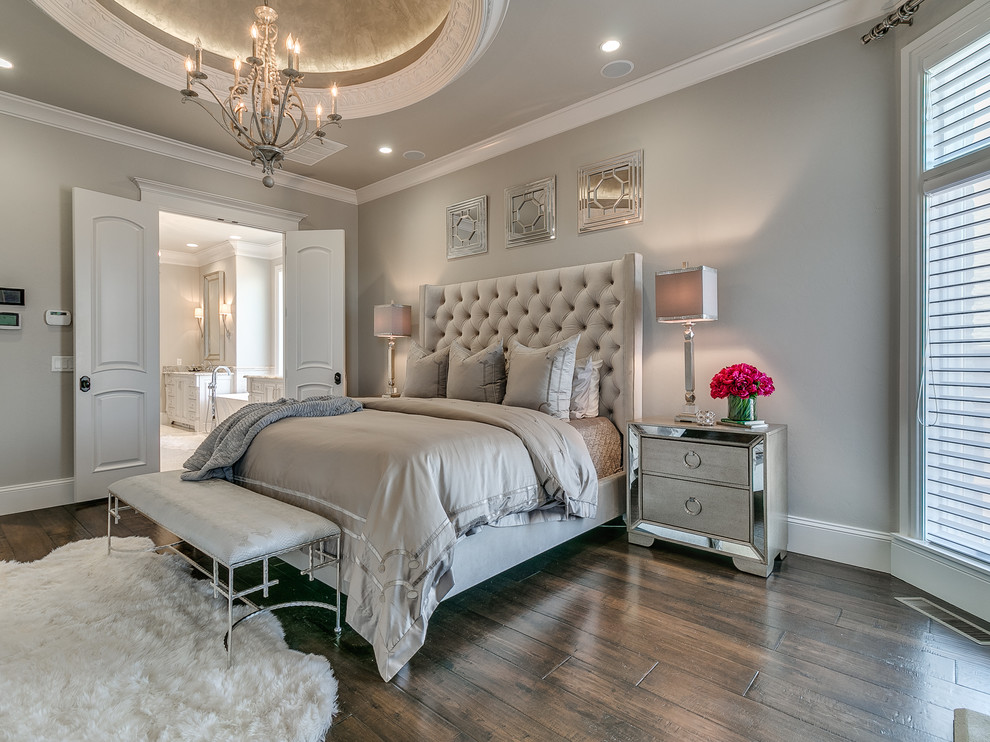 Inspiration for a large transitional master bedroom in Oklahoma City with beige walls, dark hardwood floors, a standard fireplace, a stone fireplace surround and brown floor.