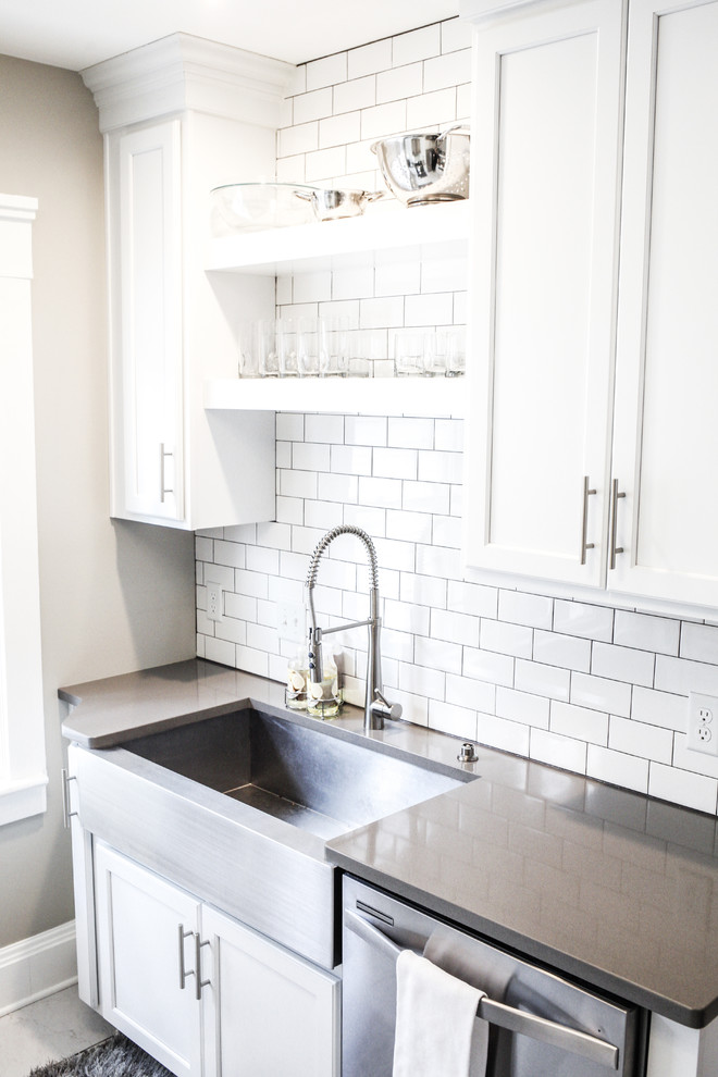Small transitional u-shaped porcelain tile and white floor enclosed kitchen photo with a farmhouse sink, shaker cabinets, white cabinets, quartz countertops, white backsplash, ceramic backsplash, stainless steel appliances, no island and gray countertops